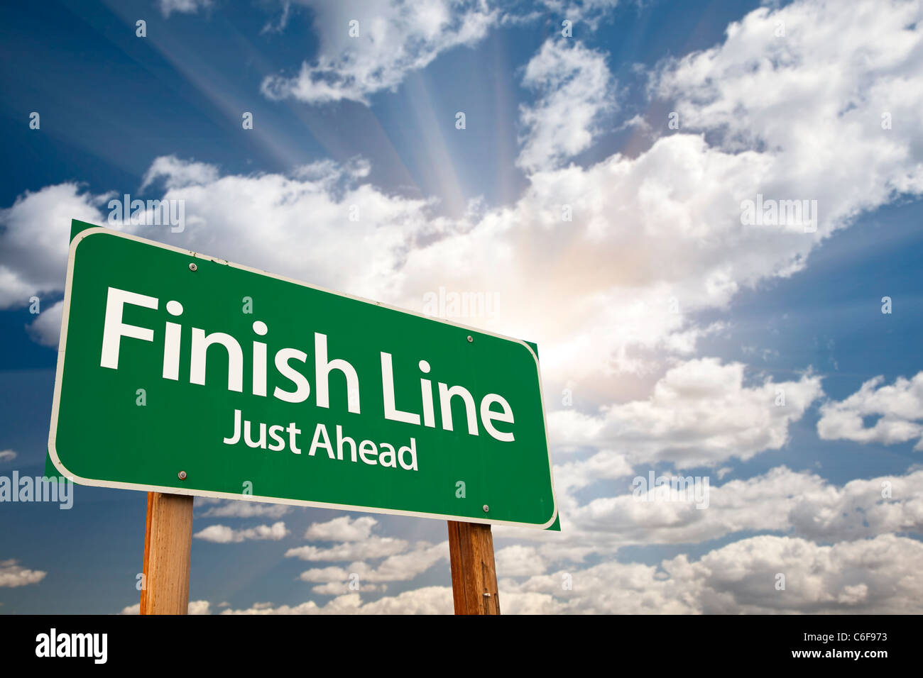 Finish Line, kurz vor grünen Schild über dramatische Himmel, Wolken und Sunburst. Stockfoto