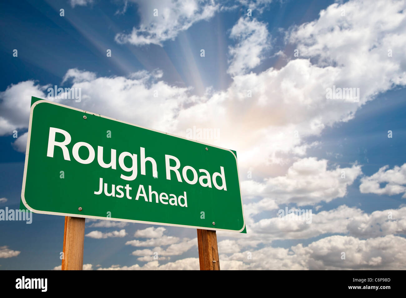 Rauhe Straße, direkt vor Ihnen grün Straßenschild über die dramatische Himmel, Wolken und Sunburst. Stockfoto