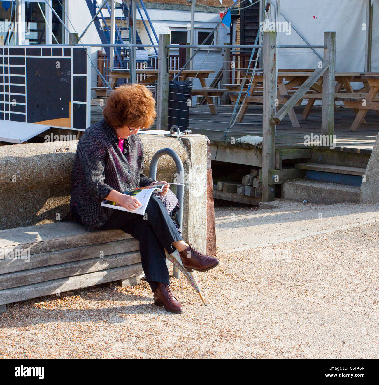 Frau am Strand von Whitstable Magazin lesen Stockfoto