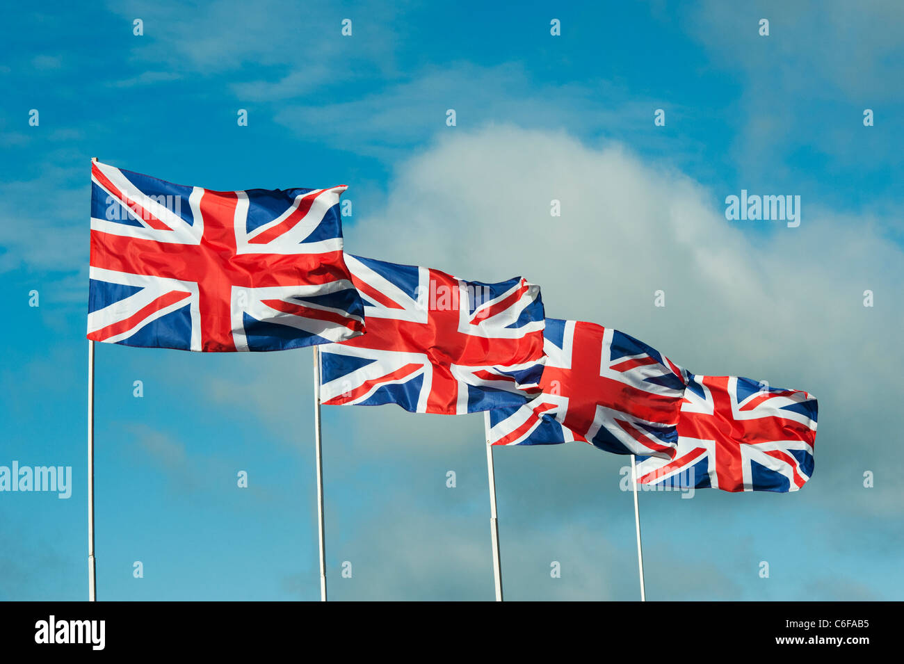 Vier Union Jack Fahnen flattern im Wind vor blauem Himmel Stockfoto