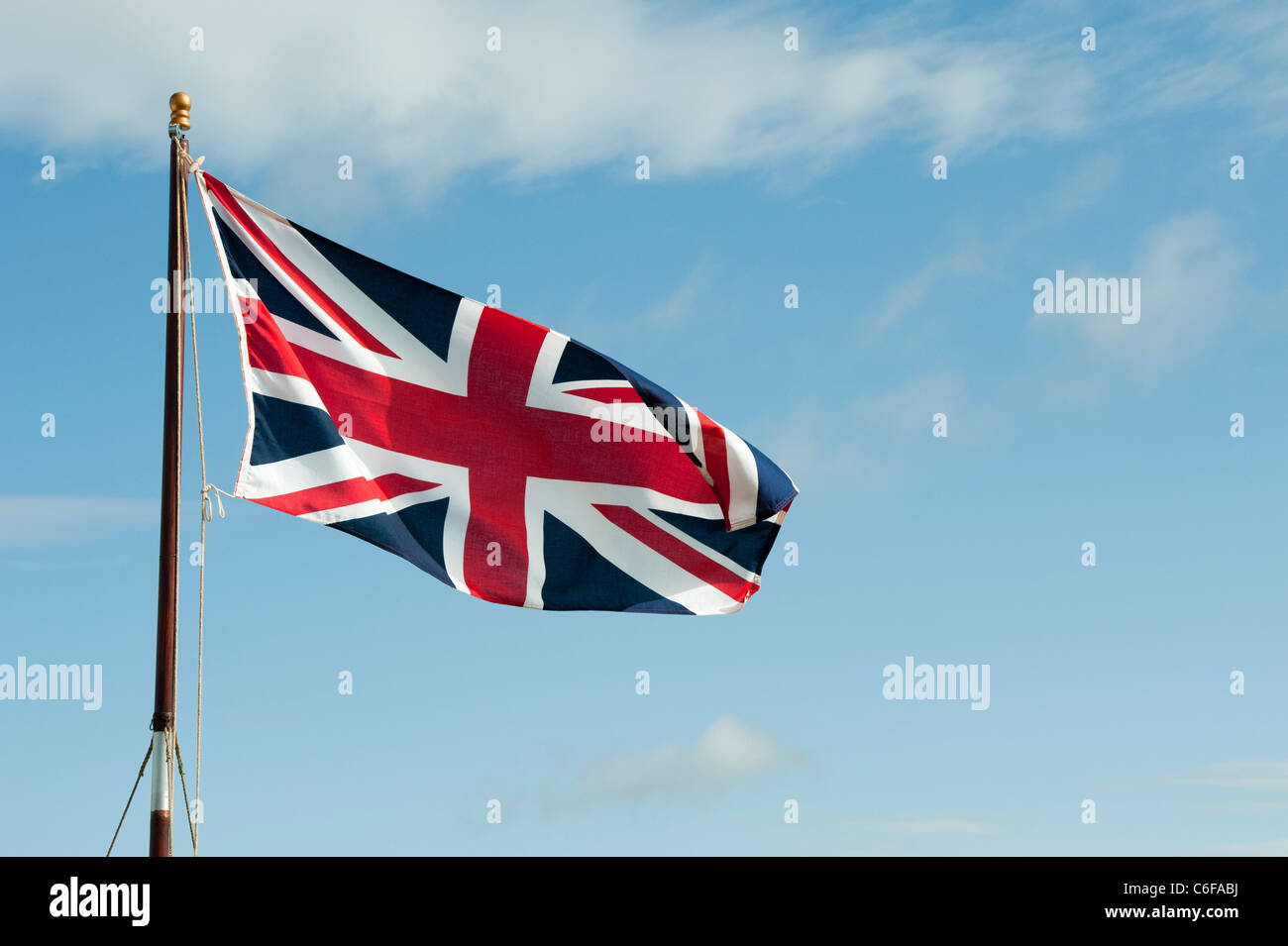 Union Jack Flagge im Wind knattern vor blauem Himmel Stockfoto