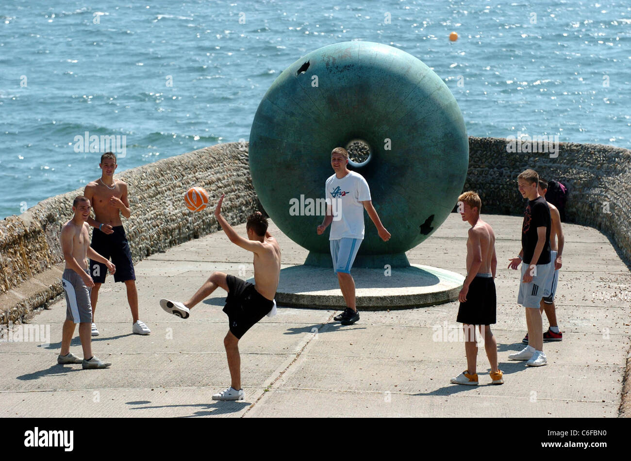 Eine Gruppe junger Männer spielt Fußball auf einem Groyne am Brighton Beach in Großbritannien Stockfoto