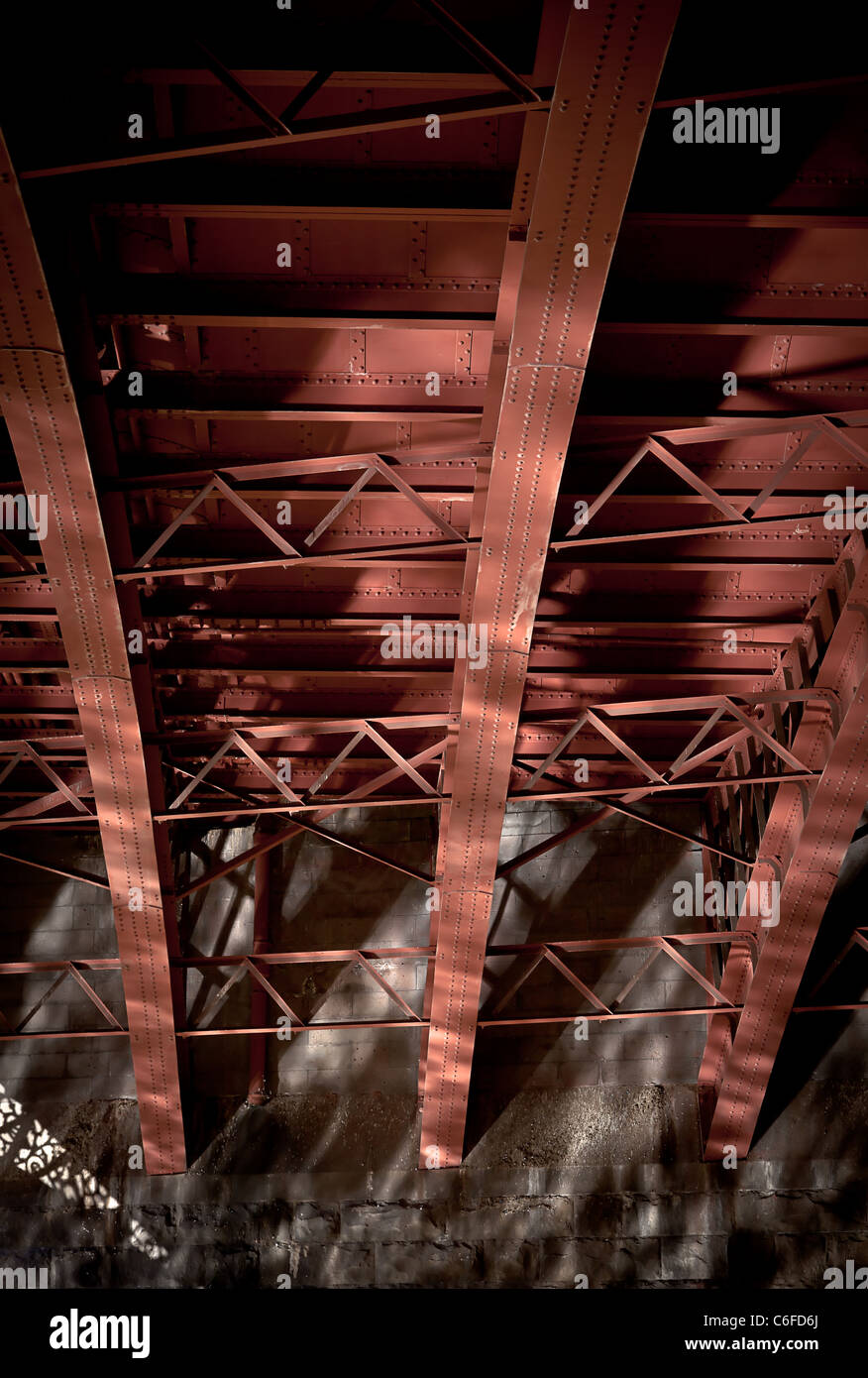 Rote Stahlträger unter einer Brücke mit Reflexionen Stockfoto