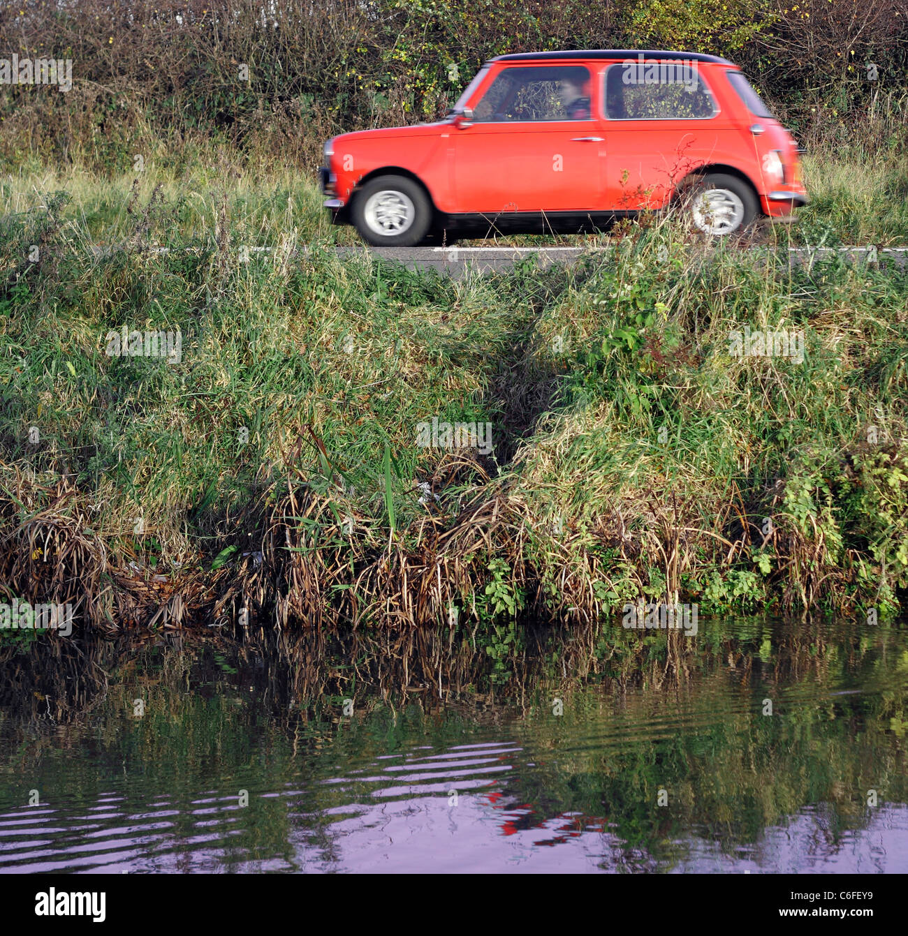 Eine rote Austin Mini Reise entlang einer Landstraße neben dem Nottingham Kanal, unscharf verschwommen, als es von Geschwindigkeiten. Stockfoto