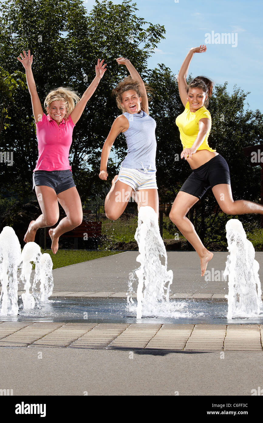 Drei junge Frauen, die in einen Brunnen springen Stockfoto