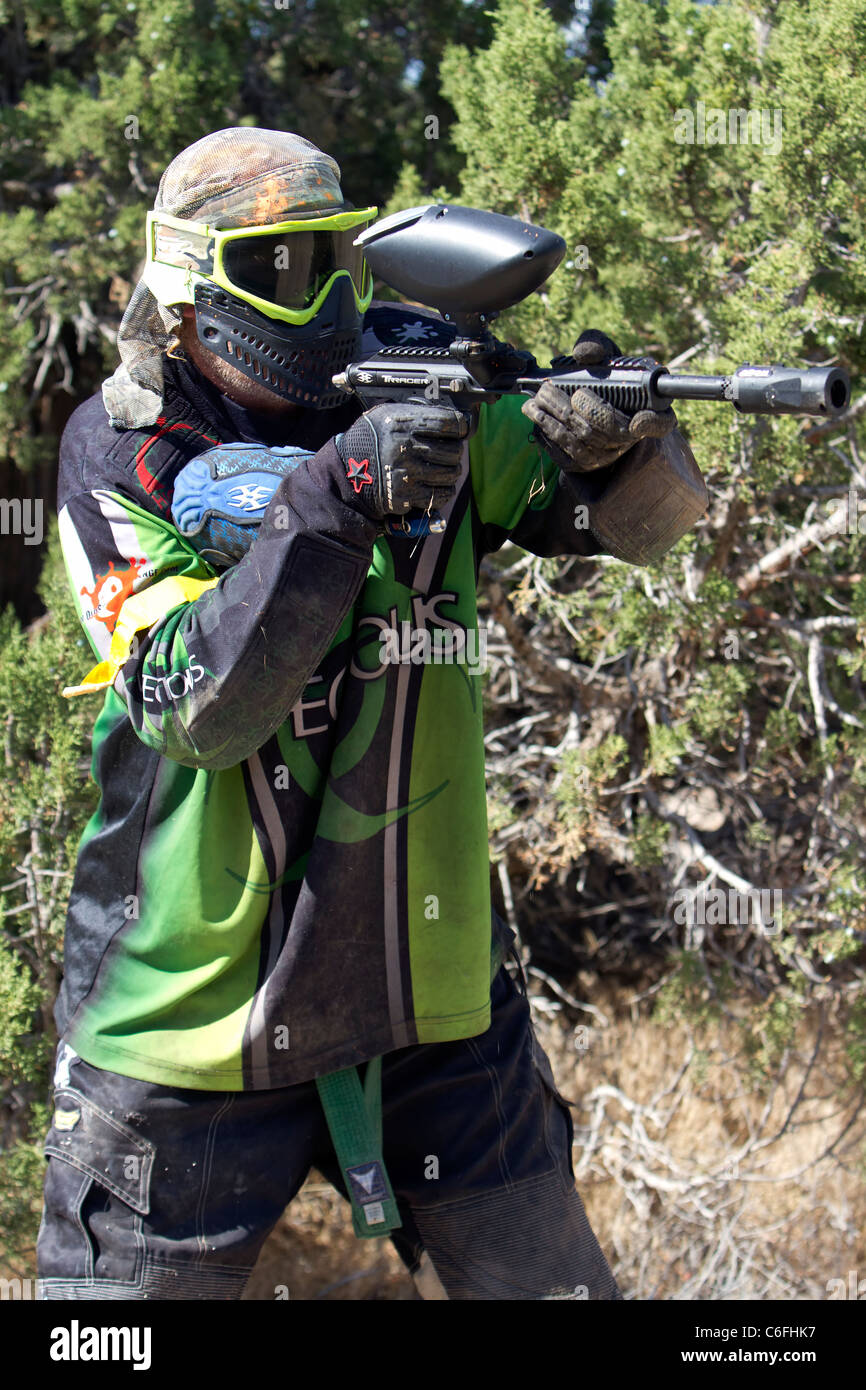 Paintball-Shooter hinter einem Baum auf feindliche Stellung und Soldaten zu schießen. Voller Schutz-Ausrüstung. Stockfoto