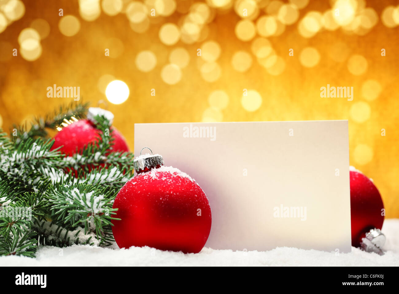 Nahaufnahme der Weihnachtskugeln, leere Karte und Tannenzweig auf festlichen Hintergrund. Stockfoto
