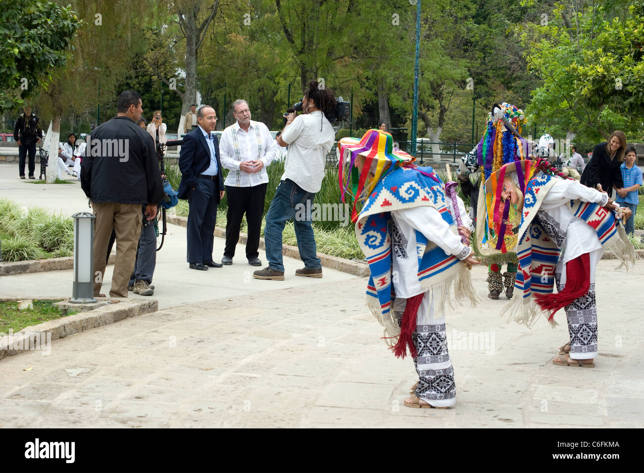 Präsident Filiman Calderon und Peter Greenberg mit kostümierten Darstellern im Park in Morelia, Mexiko, während seine Frau und sein Sohn auf ihn schauen (ganz rechts). Stockfoto