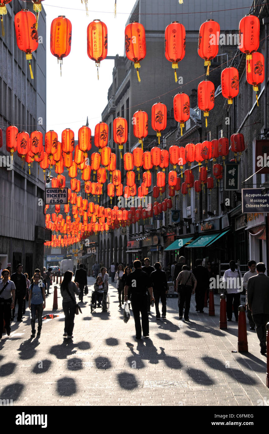 Menschen & Schatten unter Sonnenlicht auf roten chinesischen Laternen aufgehängt In der Straßenszene Chinatown ethnische Enklave in Lisle Street West Ende London England GB Stockfoto
