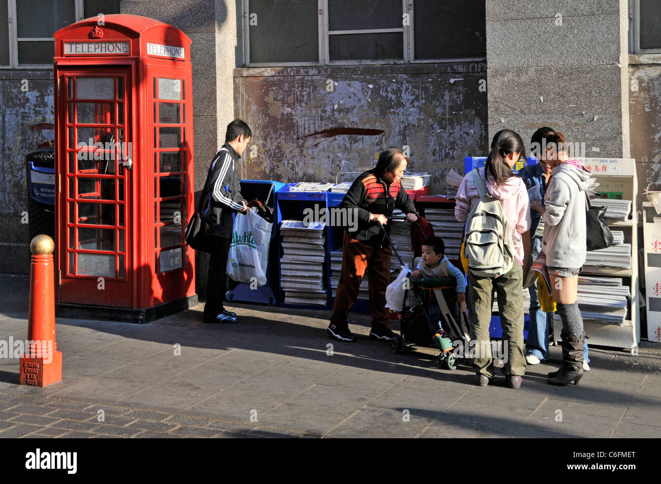 China Stadt Straßenszene Menschen helfen sich, Chinesen zu befreien Zeitung in Chinatown Gerrard Street London England Großbritannien Stockfoto