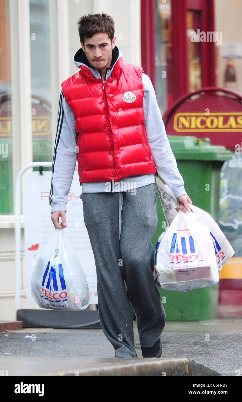 Danny Cipriani zu Fuß nach Hause, nachdem ich einige Geschäfte bei Tesco Metro, tragen einen roten Körper wärmer. London, England- Stockfoto