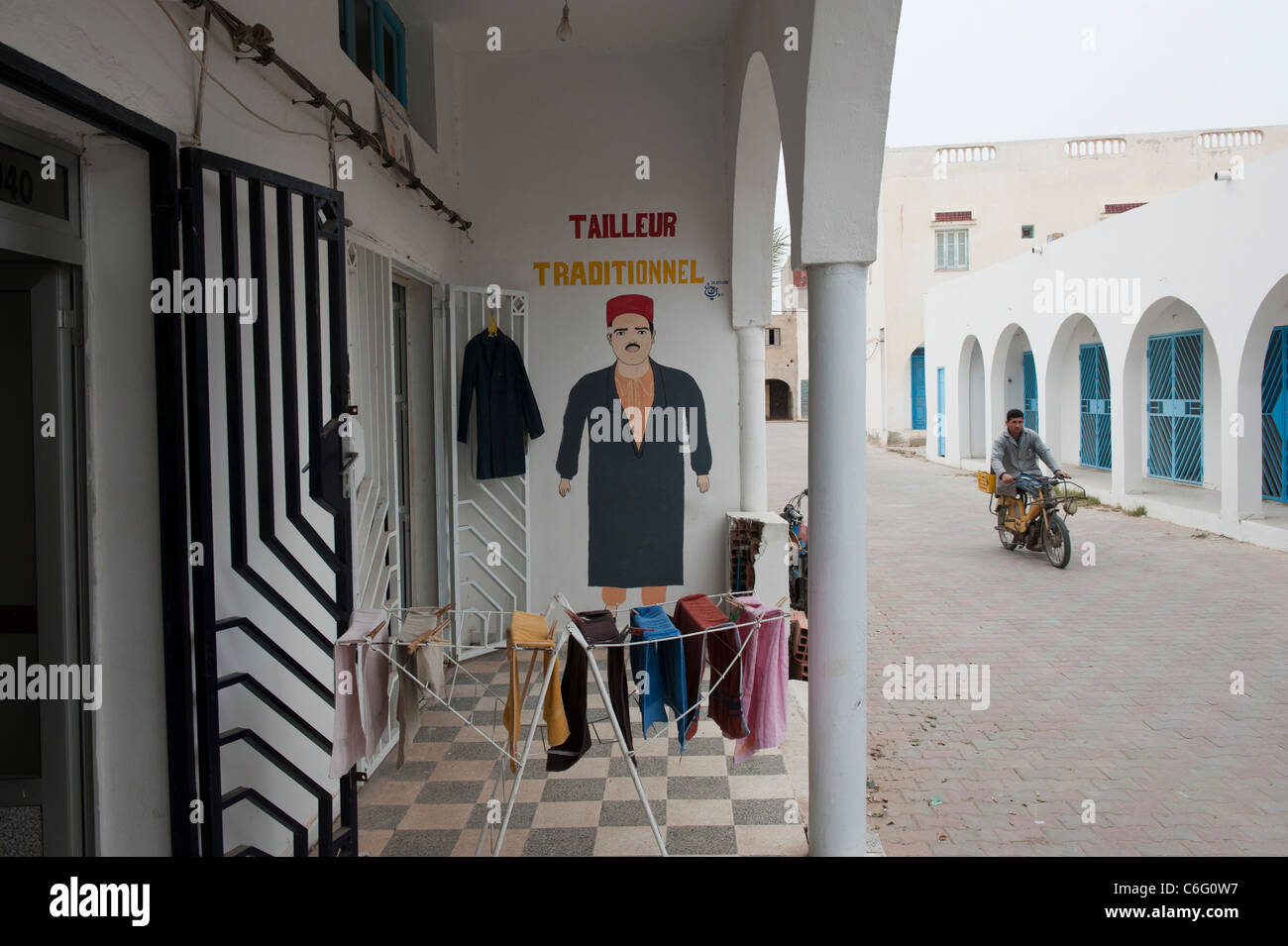 Eine tunesische auf einem kleinen Motorrad geht ein traditionelles Schneider Shop. Guellala. Djerba. Tunesien. Nordafrika Stockfoto