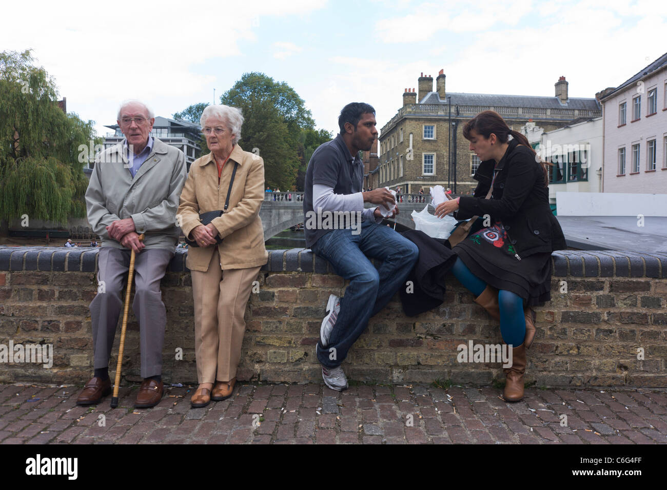 Älteres Ehepaar rest an der Cambridge-Wand wie eine jüngere, asiatischen Mann und Europäerin Essen. Stockfoto