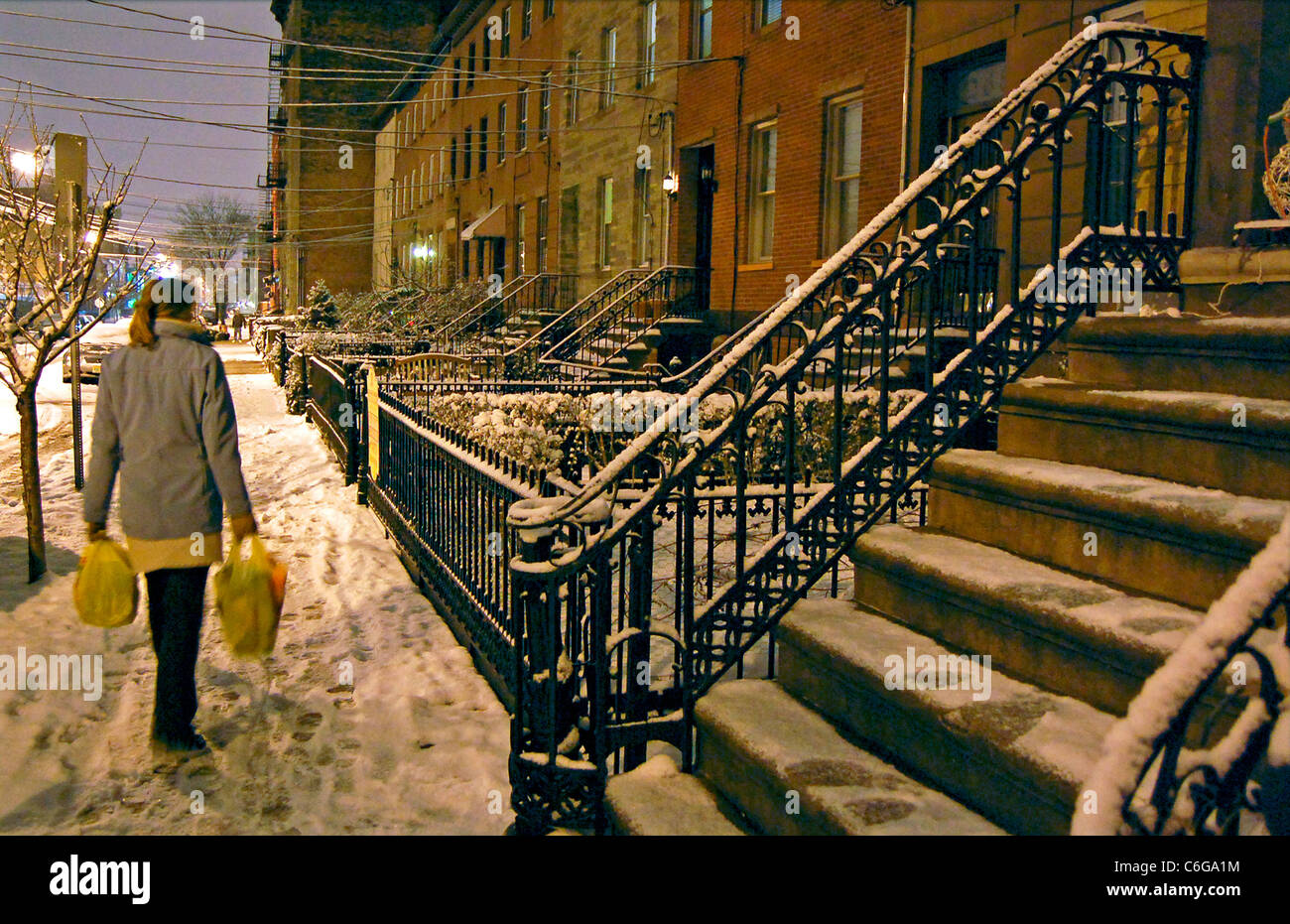 Frau zu Fuß im Schnee in der Nacht mit Lebensmitteln Stockfoto