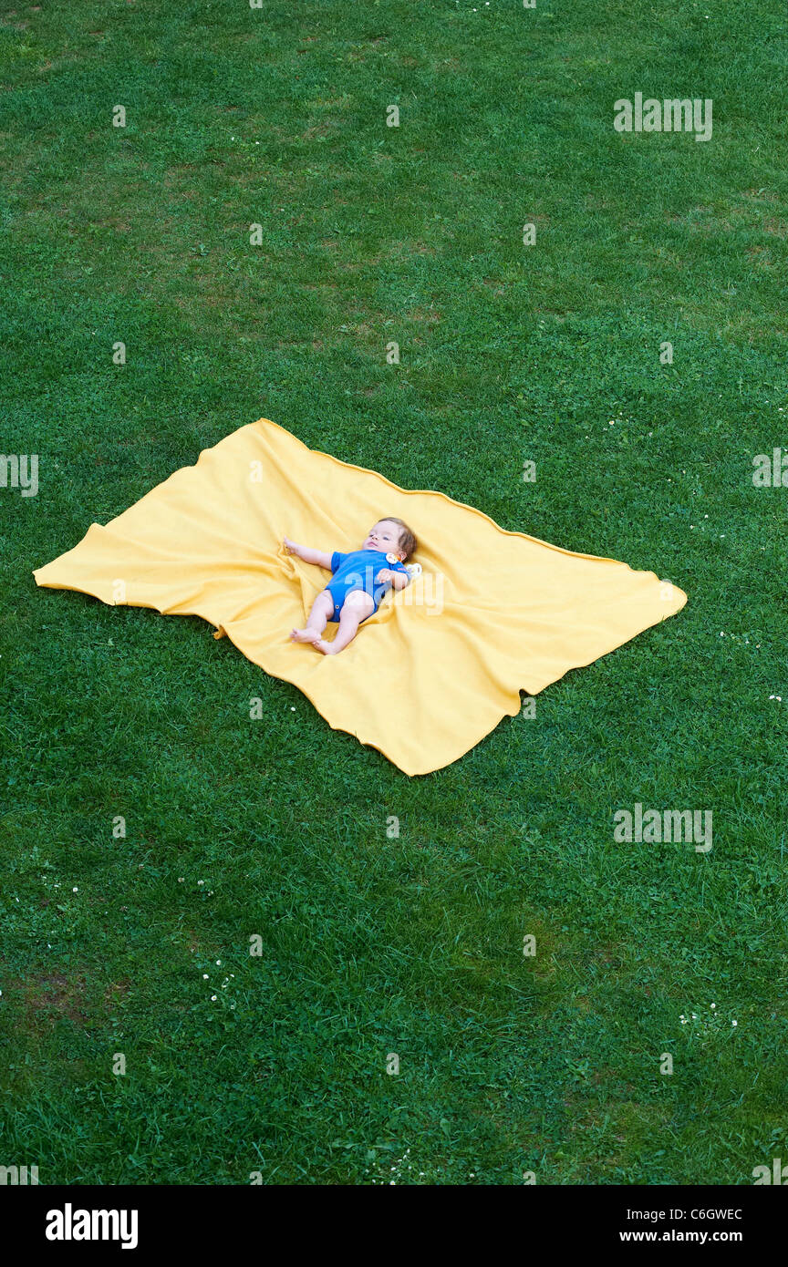 Porträt von kleines Kind Mädchen auf gelben Decke im grünen Rasen außerhalb liegend Stockfoto