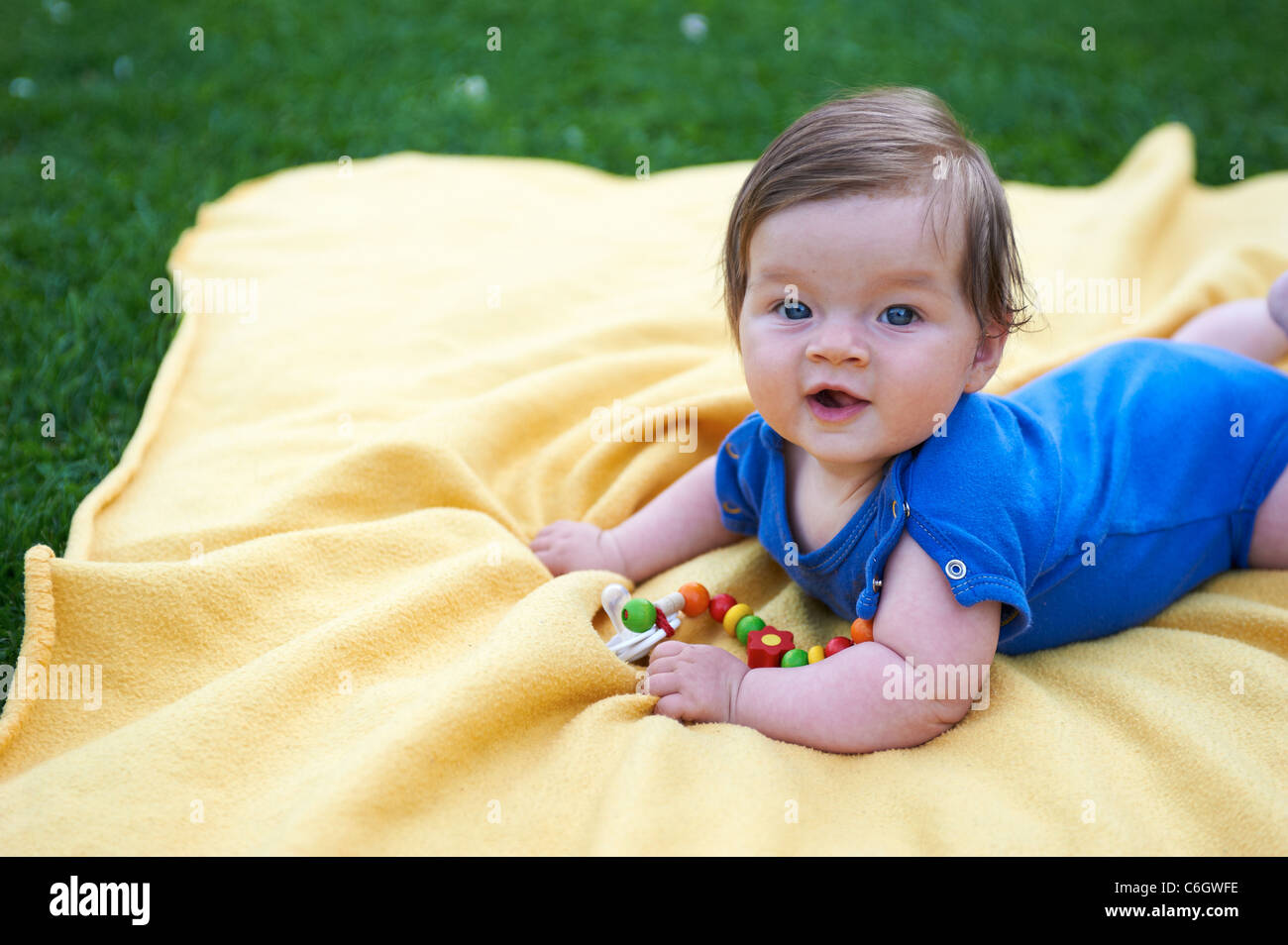 Porträt von kleines Kind Mädchen auf gelben Decke im grünen Rasen außerhalb liegend Stockfoto