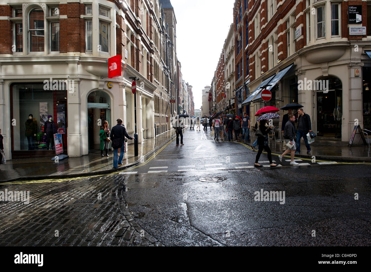 Eine Sommer-Regen-Dusche fällt auf Shopper in Covent Garden in London. Stockfoto