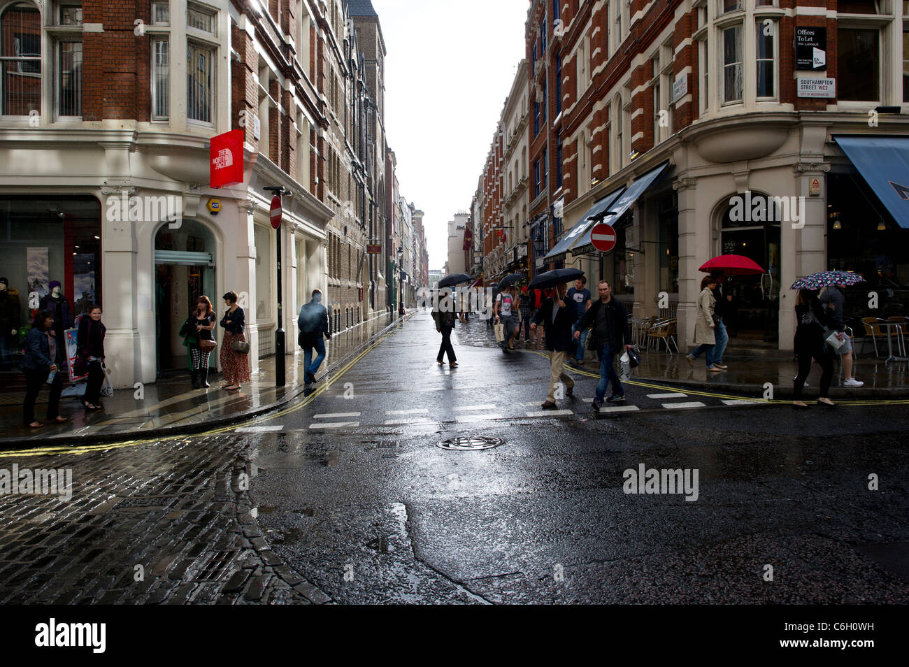 Eine Sommer-Regen-Dusche fällt auf Shopper in Covent Garden in London. Stockfoto