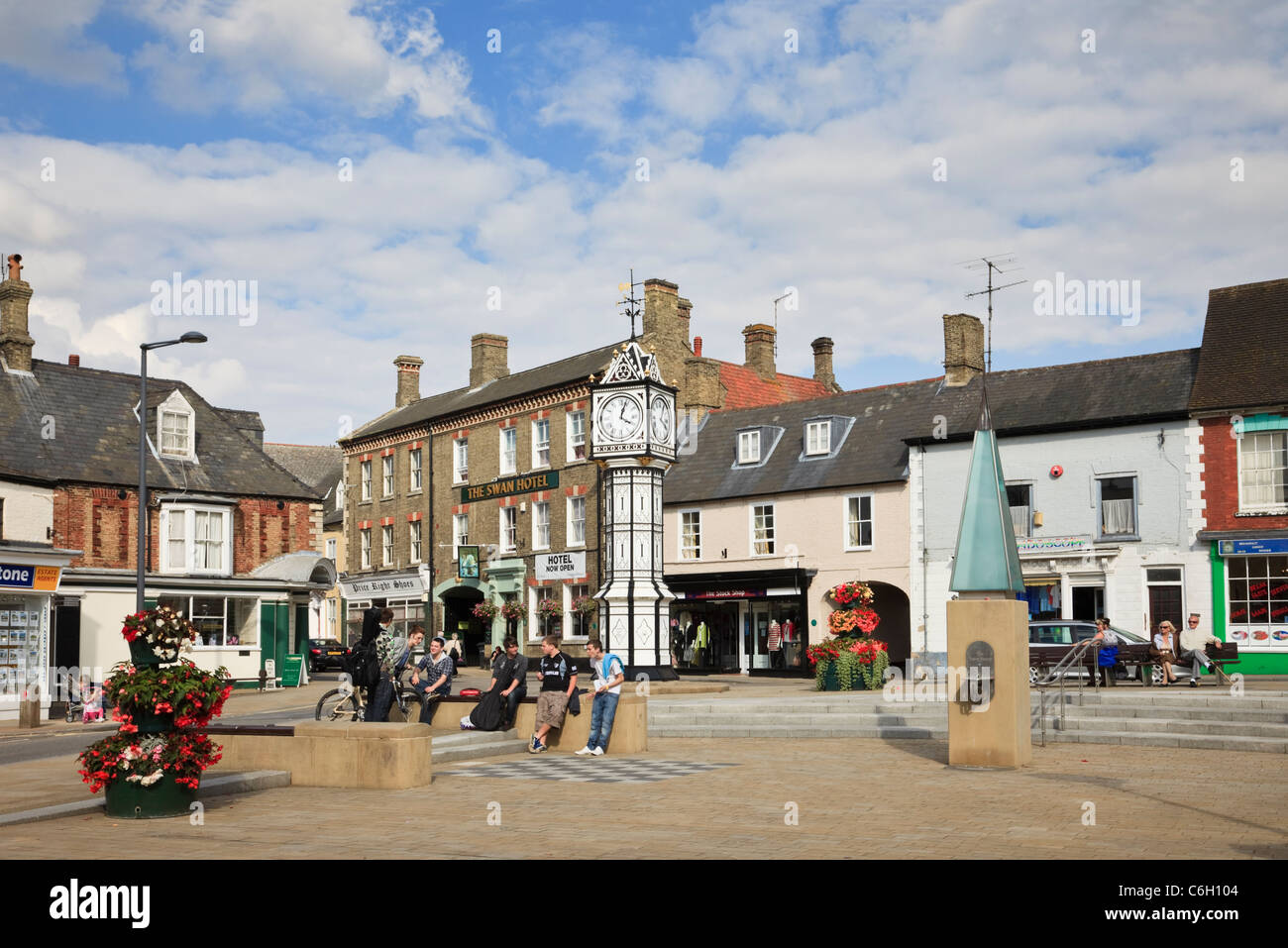 Die Menschen in den gepflasterten Marktplatz Sitzen mit dem alten reich verzierten öffentliche Uhr und Wasserpumpe. Downham Market, Norfolk, England, Großbritannien, Großbritannien Stockfoto