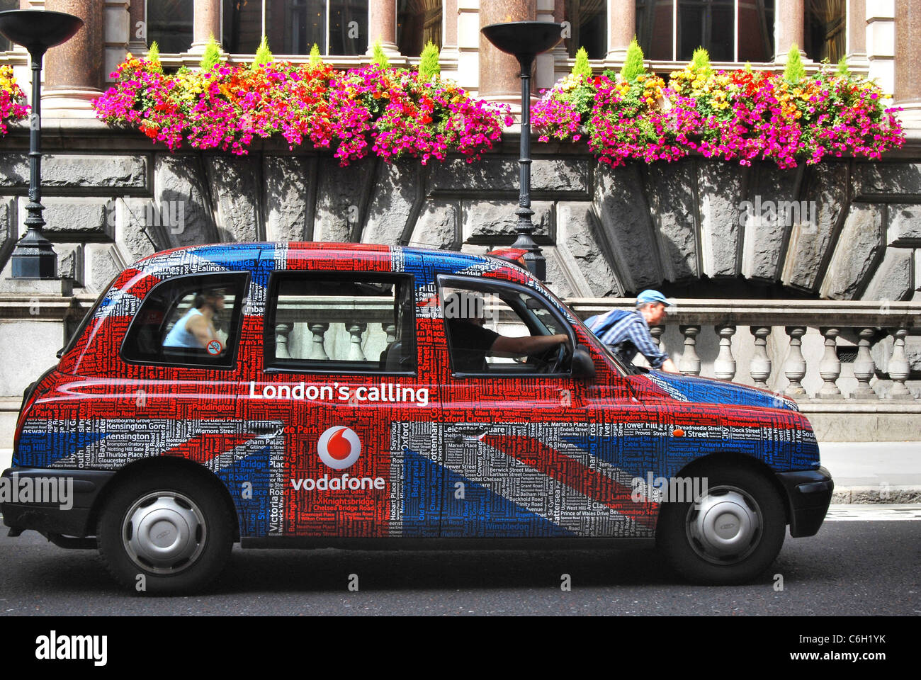 London Taxi mit Union Jack Typ Werbung Livree übergibt das Ale und Pie House Pub mit seinen bunten Schaufenster von Blumen Stockfoto