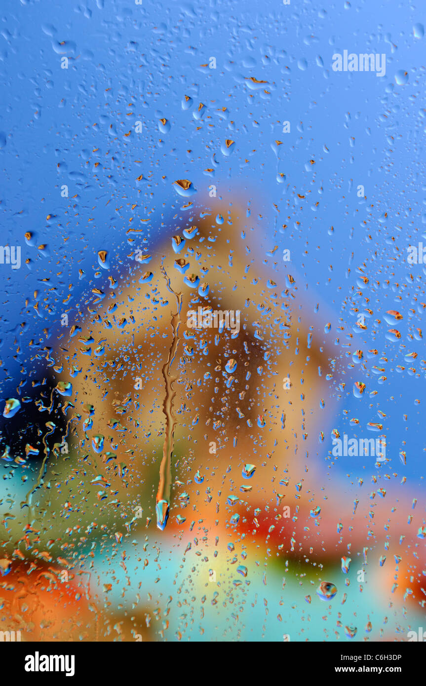 Konzeptionelle stock Foto von Out of Focus Landhaus unter blauem Himmel hinter nassen Glas bei Regenwetter Stockfoto