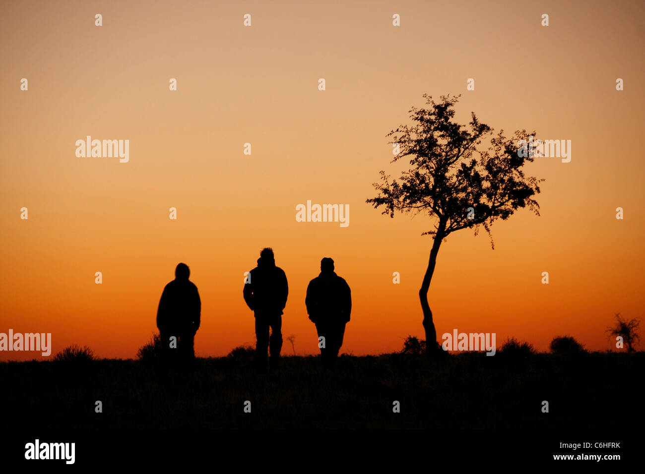 Drei Wanderer Silhouette bei Sonnenuntergang in Wüstenlandschaft Stockfoto