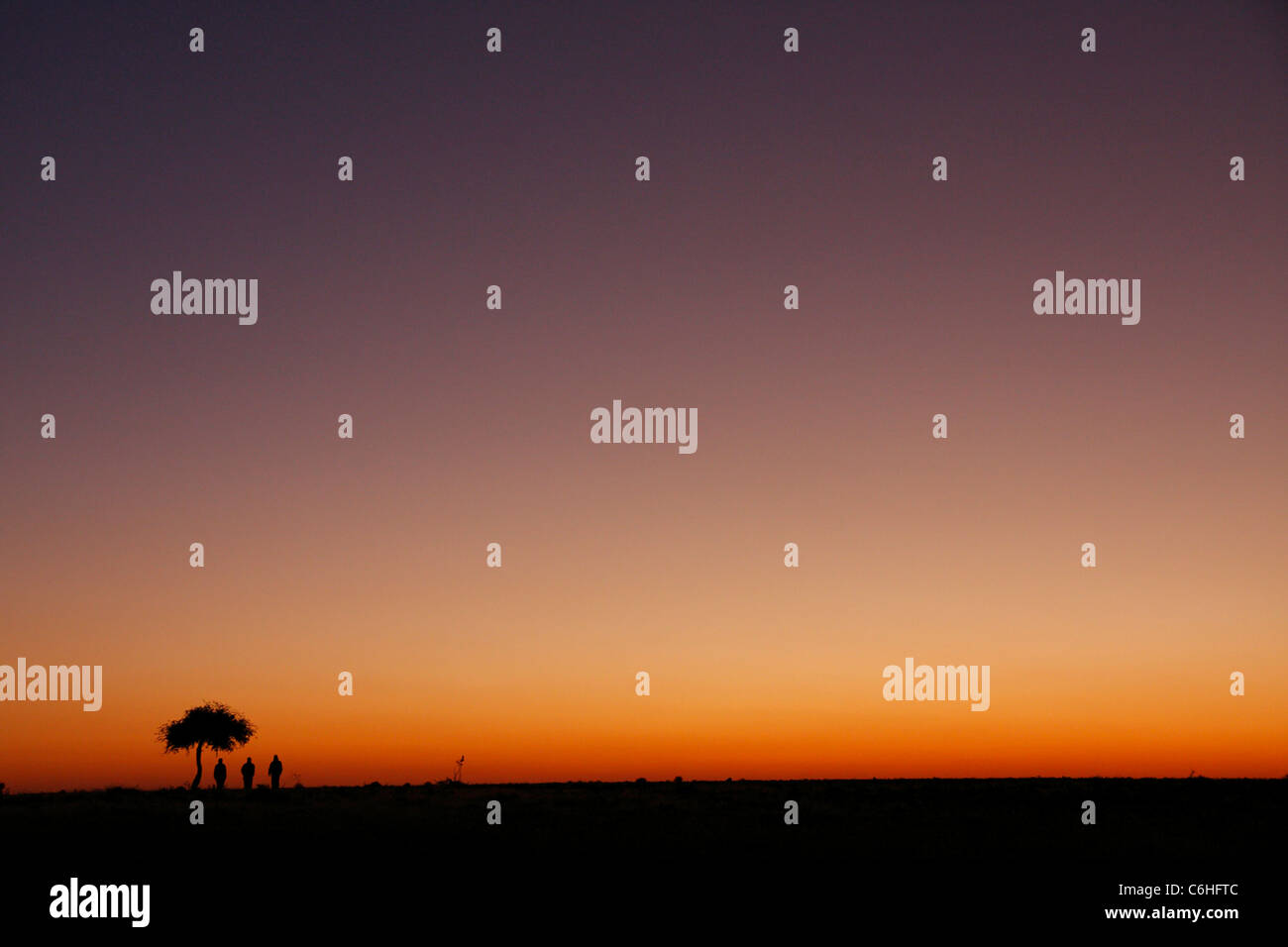 Drei Wanderer Silhouette bei Sonnenuntergang in Wüstenlandschaft Stockfoto