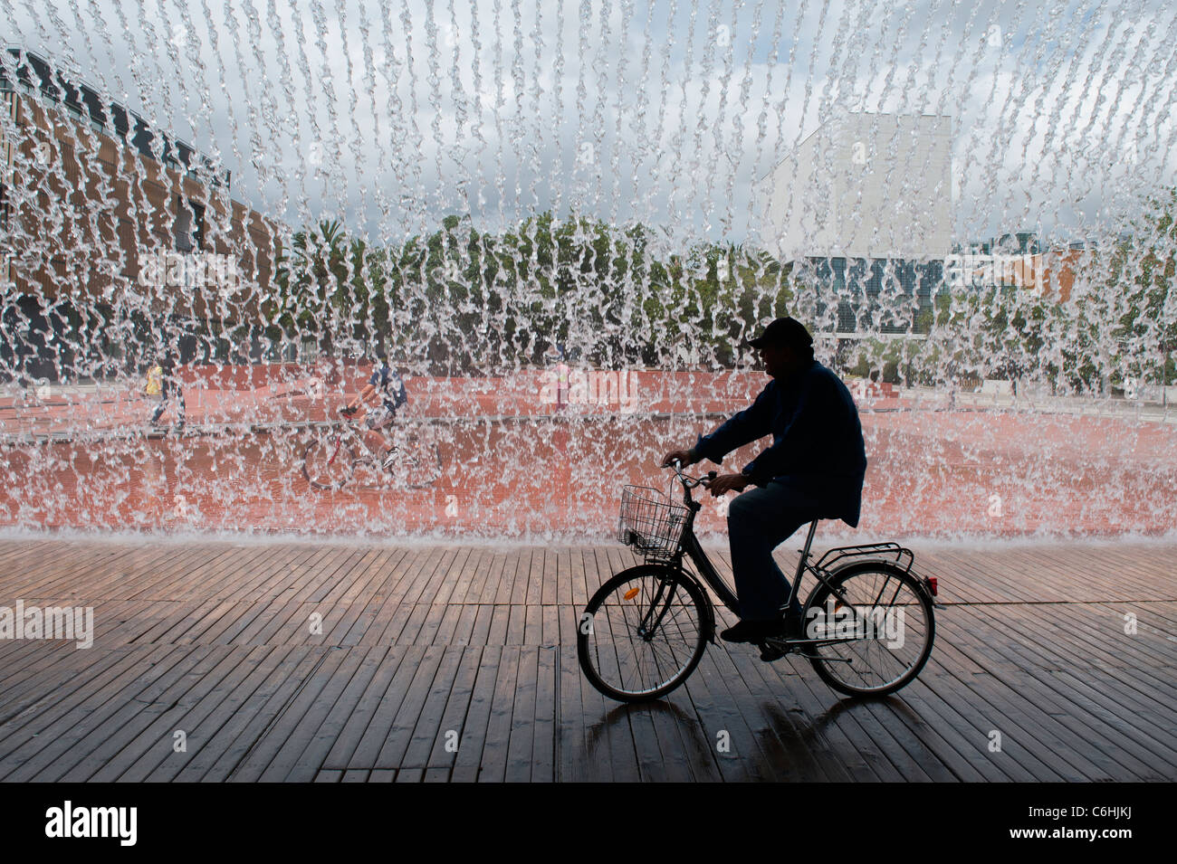 Mann auf dem Fahrrad Unterquerung eines Brunnens, Parque Das Nações (Park der Nationen), Lissabon, Portugal Stockfoto