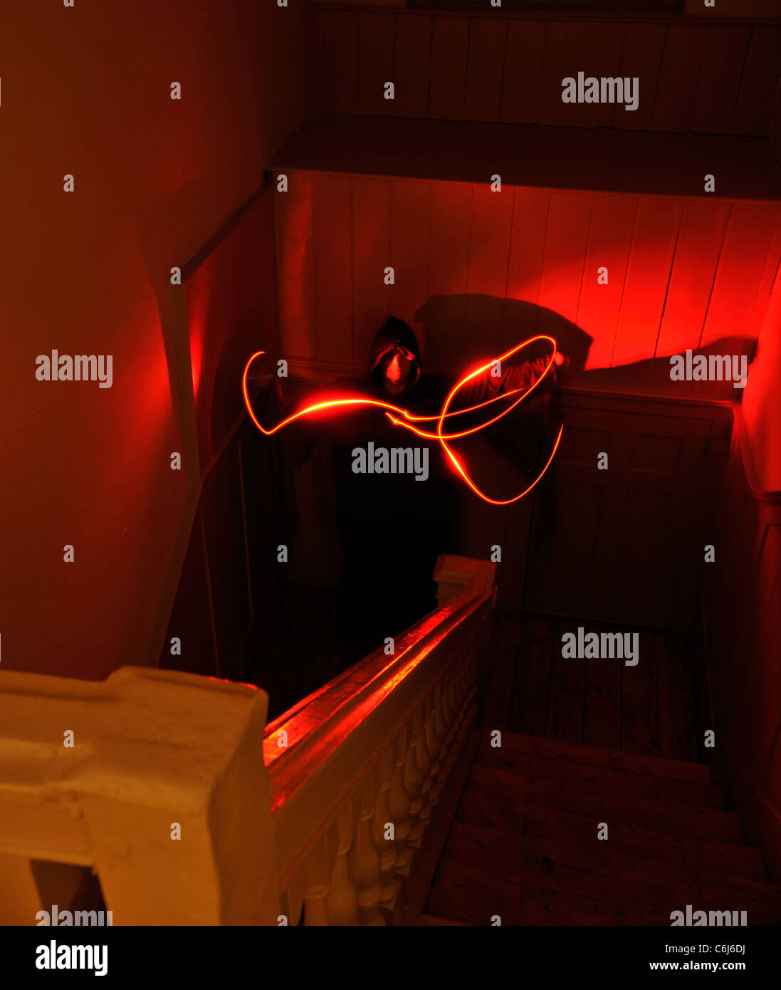 Geisterhafte Figur winkt ein rotes Licht stehen in einem Treppenhaus Stockfoto