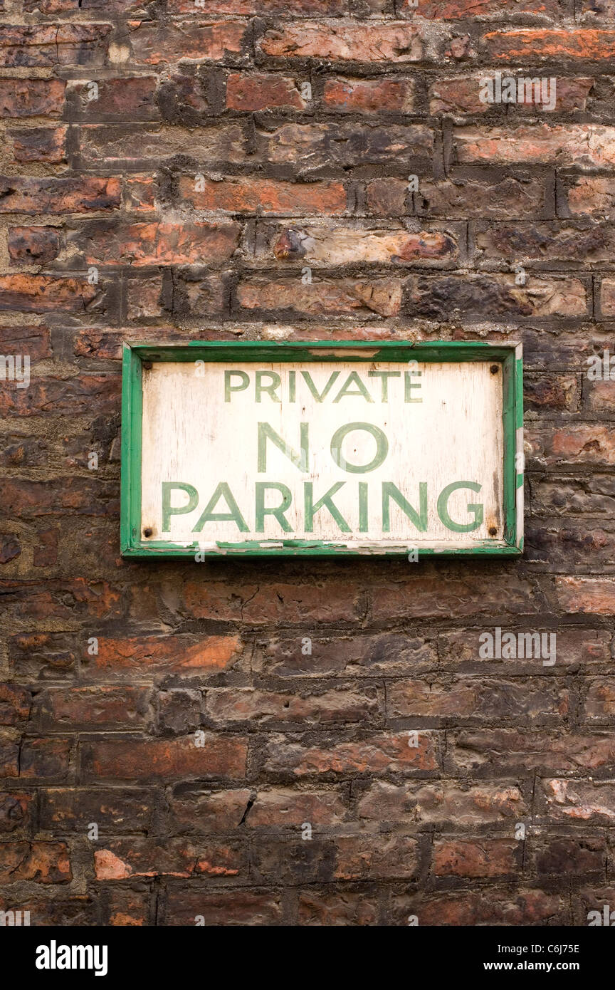 Altmodische keine Parkplatz-Schild mit Schmerzen auf einer roten Backsteinmauer bröckelt Stockfoto