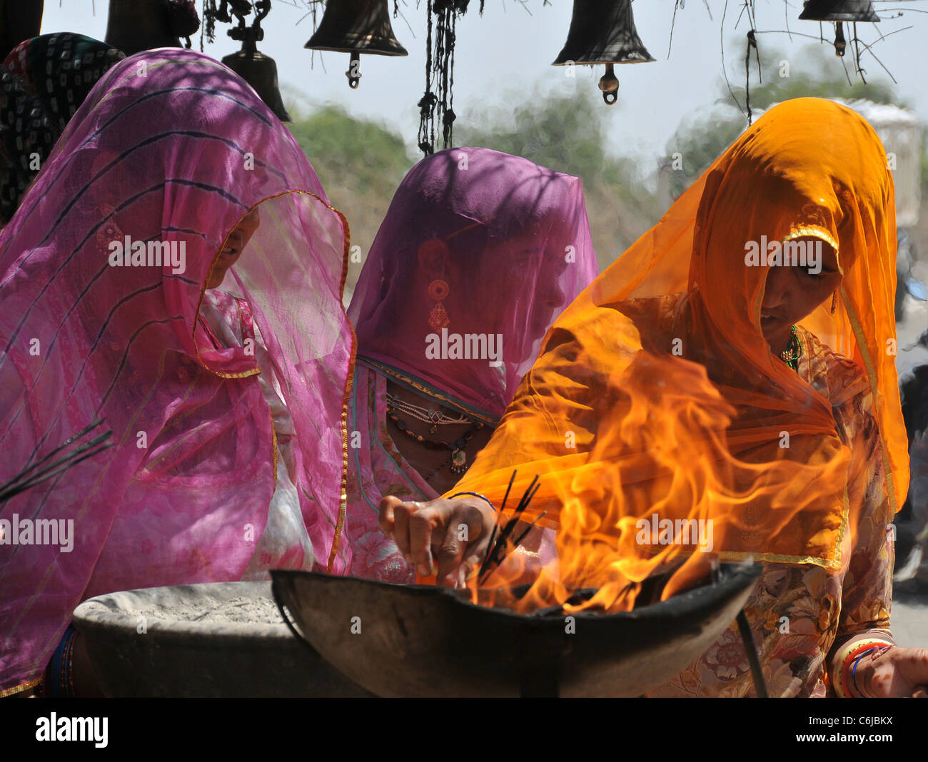 Drei Frauen, die Beleuchtung aus Feuer Schale Indianerin Räucherstäbchen an beten verändern Aravalli Hills Rajasthan Indien Stockfoto