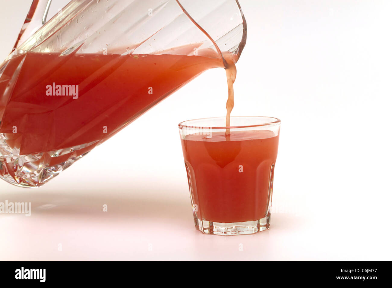 Gießen ein Glas frisch gepressten rosa Grapefruitsaft auf weißem Hintergrund Stockfoto