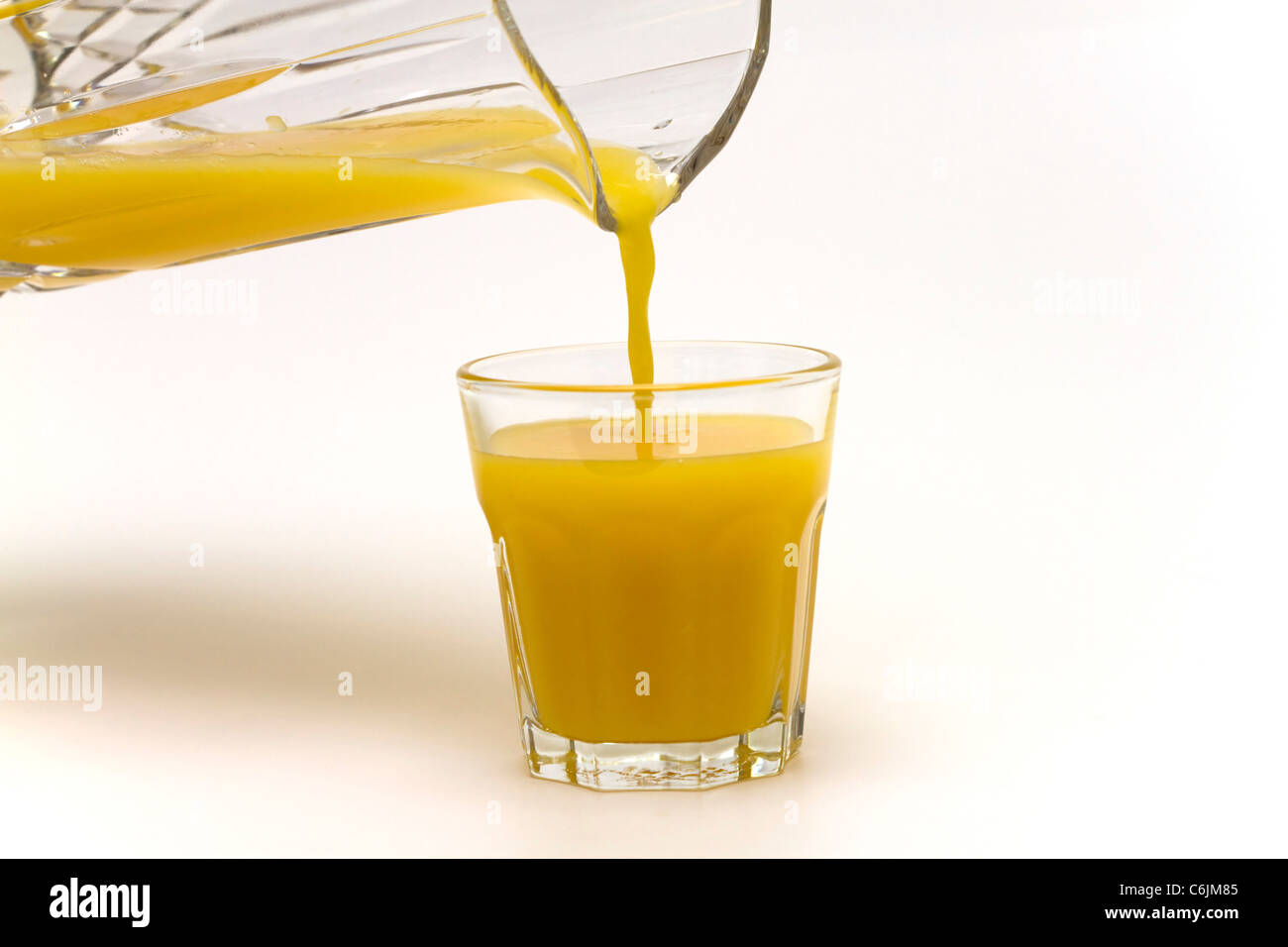 Gießen ein Glas frisch gepressten Orangensaft auf weißem Hintergrund Stockfoto
