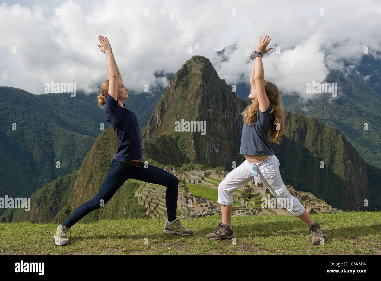 Teenage Mädchen tun, Krieger 1 Pose mit Die verlorene Stadt der Inkas im Hintergrund, Machu Picchu, Cusco Region, Peru Stockfoto