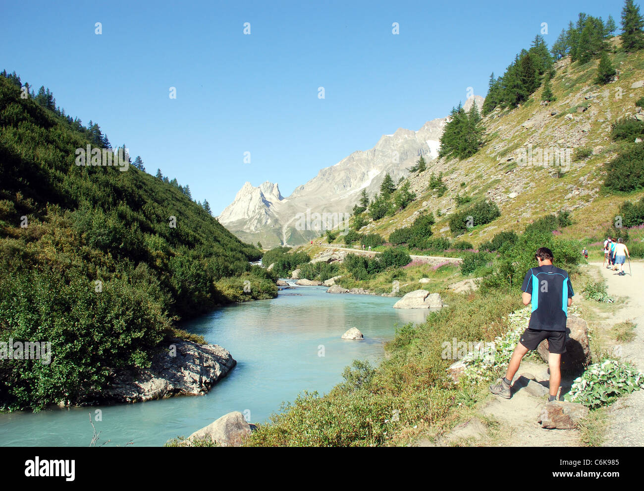 Ein Fluss fließt durch eine steile Tal in den Alpen in der Nähe von Mont Blanc mit den Bergen des Col Ferret im Hintergrund Stockfoto