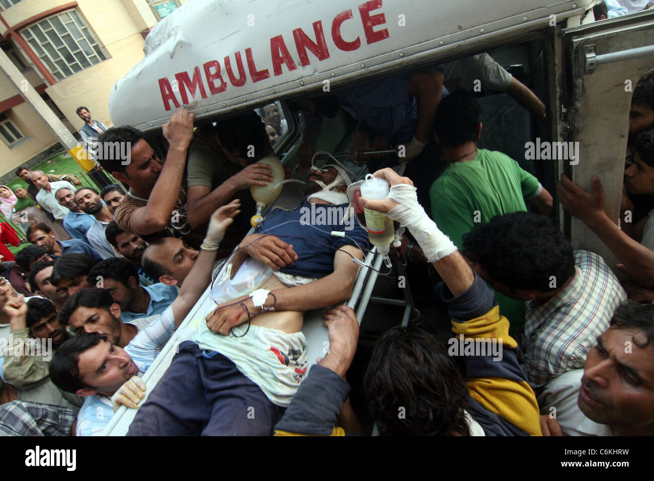 Menschen in Kaschmir tragen einen verwundeten Mann aus einen Krankenwagen außerhalb eines Krankenhauses in Srinagar 5. August 2010. Indien steht vor einer ausgewachsenen Stockfoto