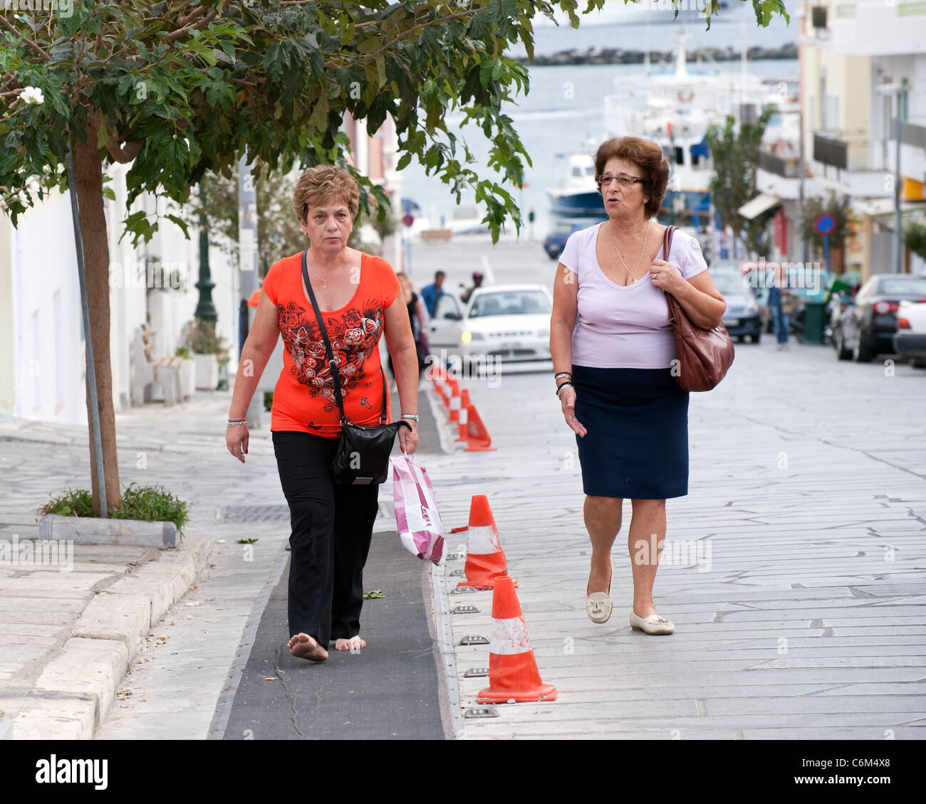 Zwei mittleren Alters griechischen Frauen gehen Leoforos Megalocharis Allee, in Tinos-Stadt auf der griechischen Kykladen Insel Tinos. Stockfoto