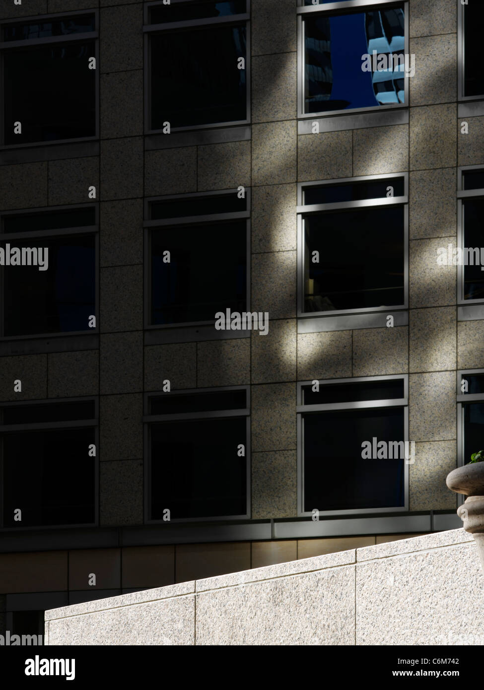 Detail der leeren Bürogebäude Plaza mit steinernen Sims bei strahlendem Sonnenschein gesehen drastisch gegen dunkle Gebäude im Hintergrund Stockfoto