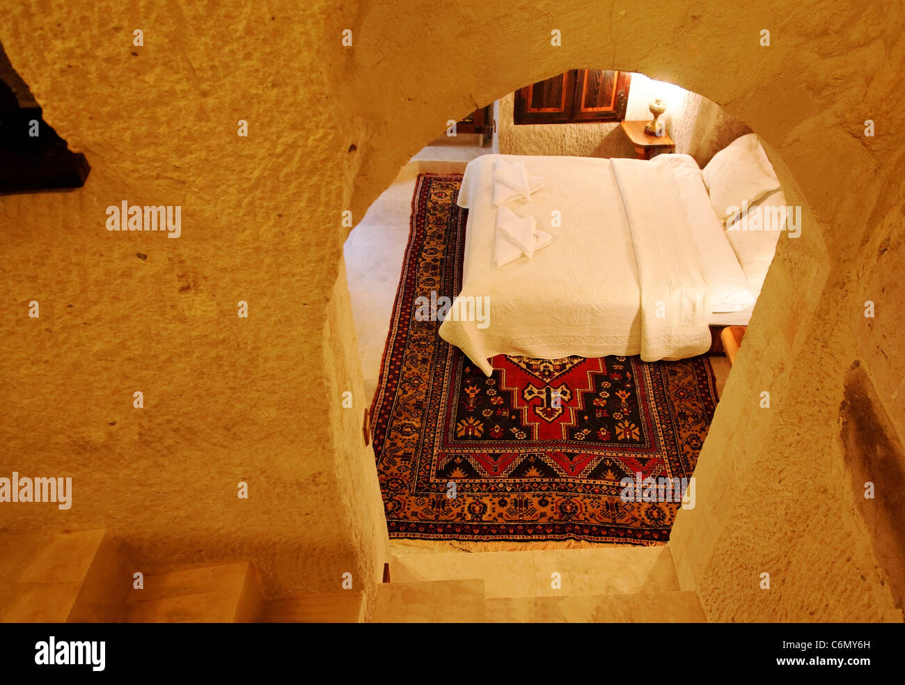 renovierte Kalkstein-Höhle-Schlafzimmer-Innenarchitektur und Layout komplett möbliert mit weißer Bettwäsche und gewebten Teppich, Landschaft Stockfoto