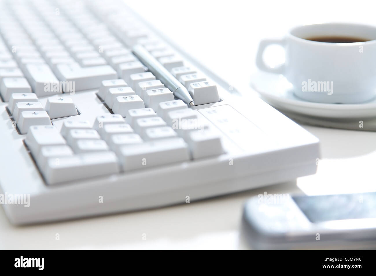 Clouse-Up weiße Tastatur, Handy, Stift und eine Tasse Kaffee auf dem desktop Stockfoto