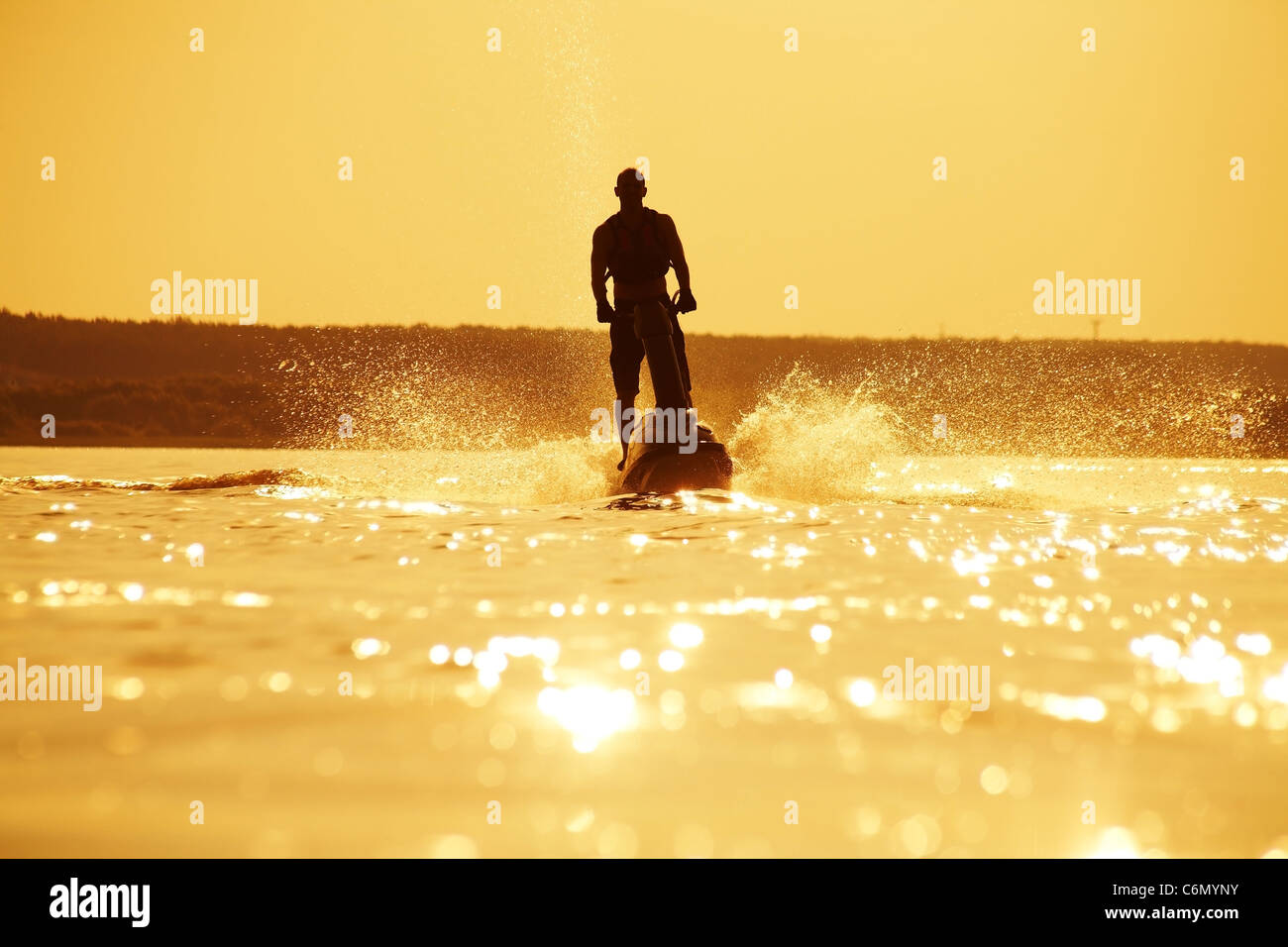 starker Mann fährt mit dem Jetski über das Wasser im Sonnenuntergang .silhouette Spray. Stockfoto