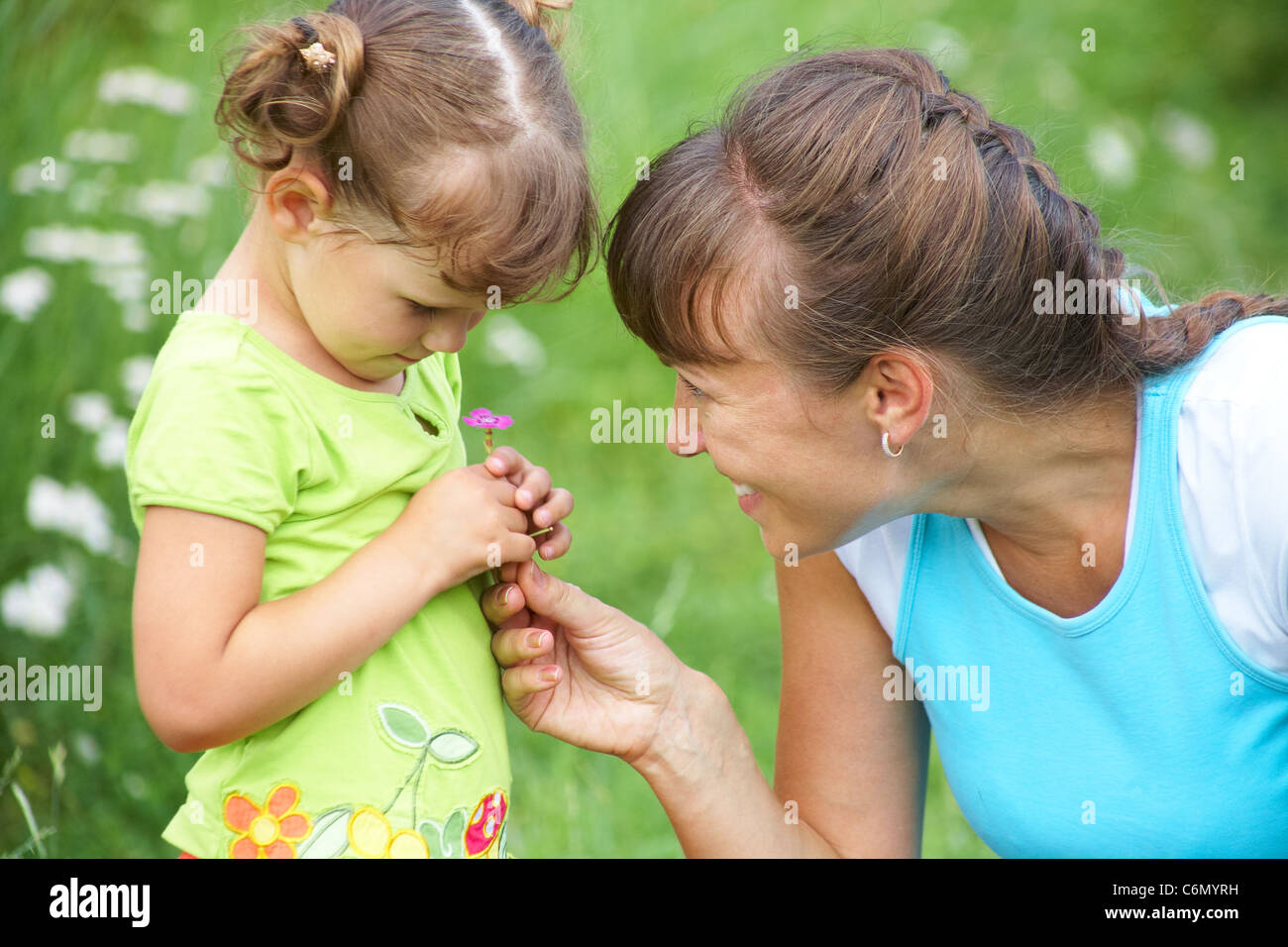 Junge Mutter tröstet ein kleines Mädchen auf einer Wiese Stockfoto