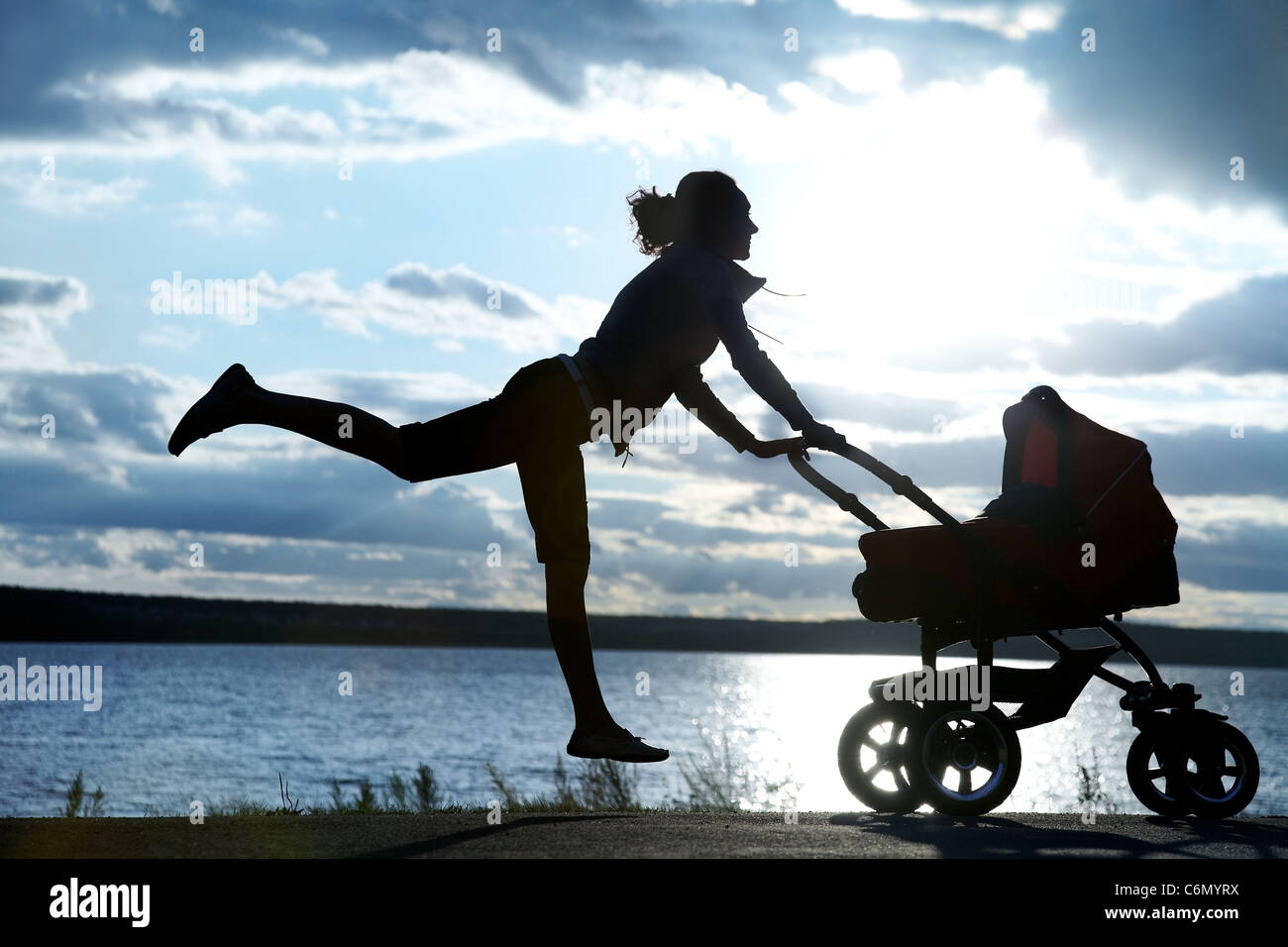 Silhouette der junge schlanke Mutter Übung mit einem Kinderwagen Stockfoto