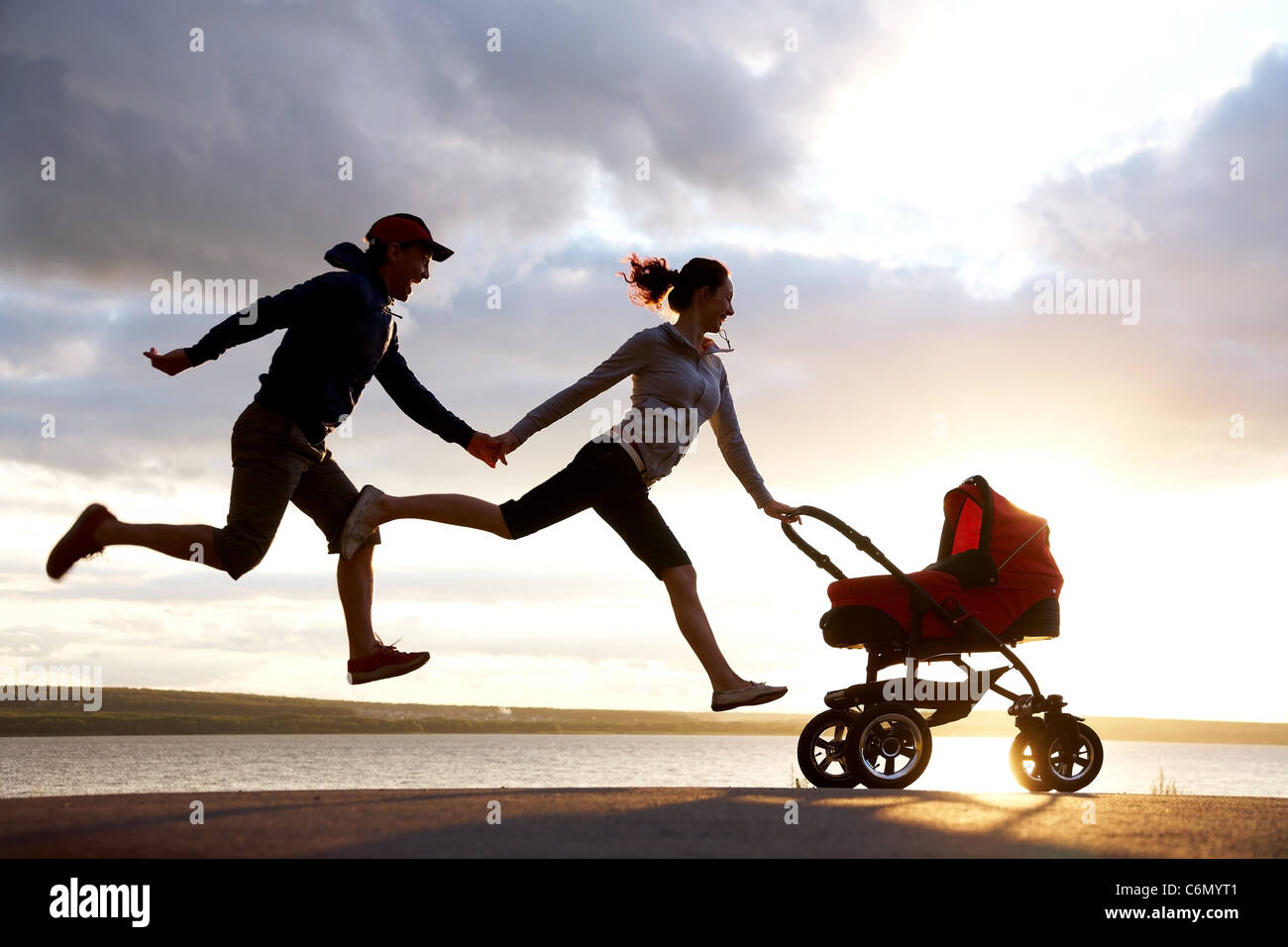 Silhouetten von glücklichen Eltern laufen für einen Kinderwagen Stockfoto