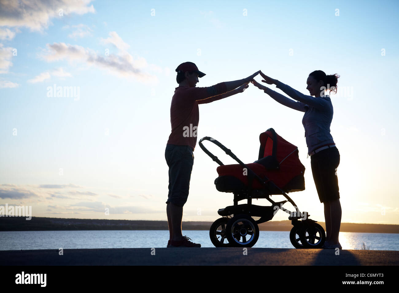 Silhouetten der Eltern schützen Sie ihr Kind in einem Kinderwagen Stockfoto