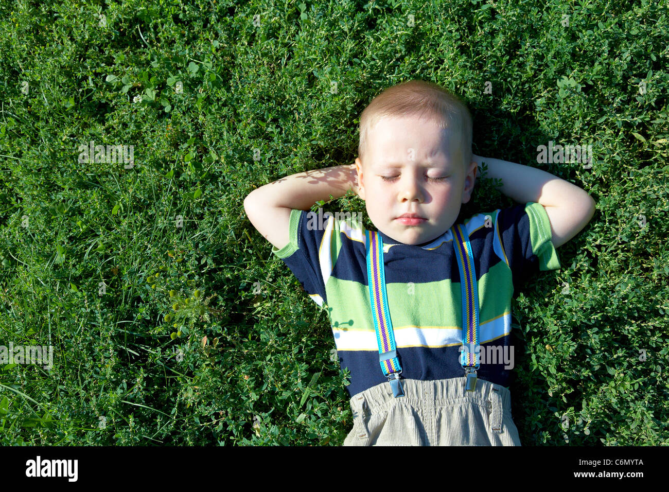 glücklich fröhliche kleine Junge schlafen auf grünen Rasen im Sommer Stockfoto