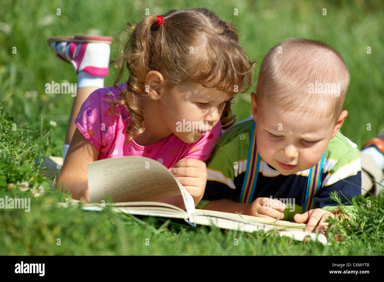 Kinder freuen sich über das Buch im grünen Rasen Stockfoto