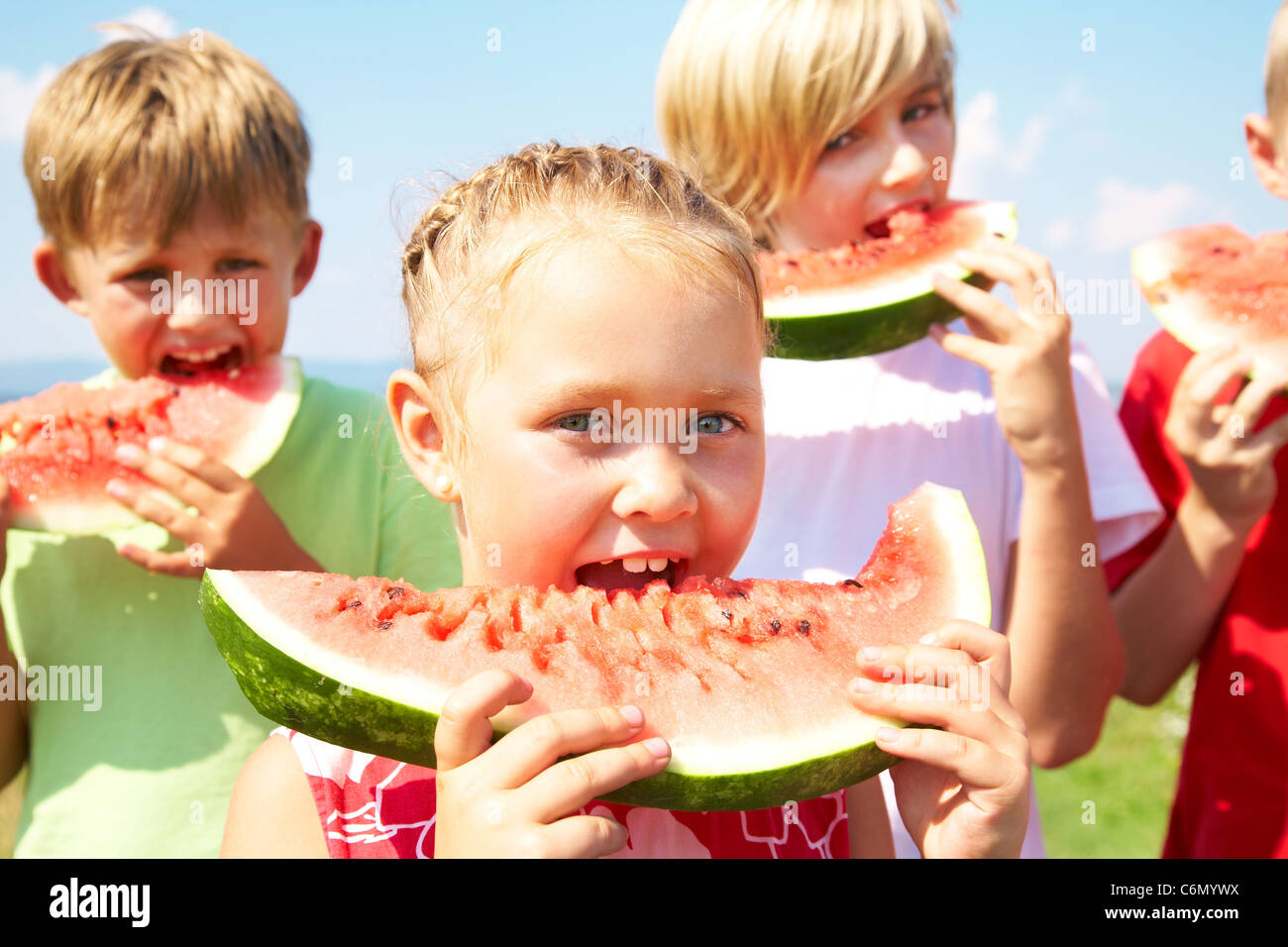 Kinder essen rote Wassermelone auf blauen Himmelshintergrund Stockfoto
