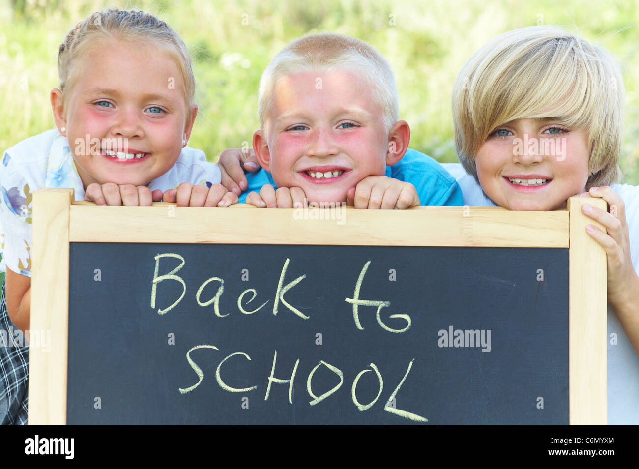 Kinder stehen neben der Tafel mit dem Text "back to School" Stockfoto