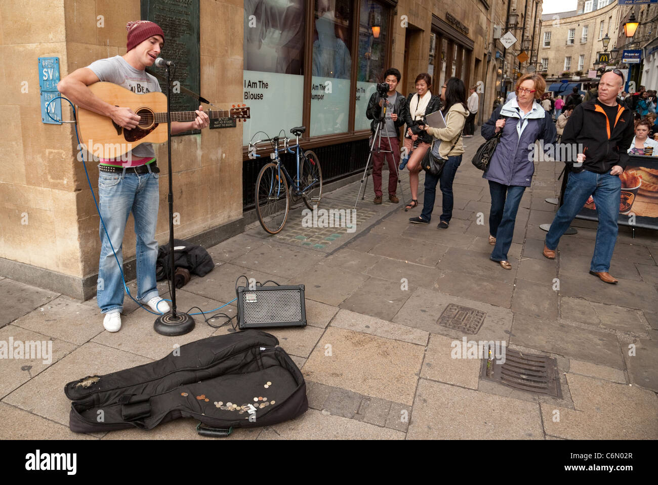Eine Straßenmusikant Gitarre spielen auf den Straßen von Cambridge von japanischen Touristen beobachtet den Markt Straße Cambridge UK Stockfoto